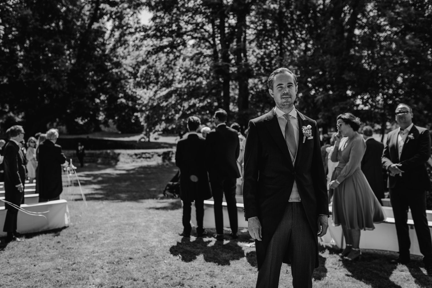 Guests gathered outdoors for a wedding ceremony in a wooded setting.