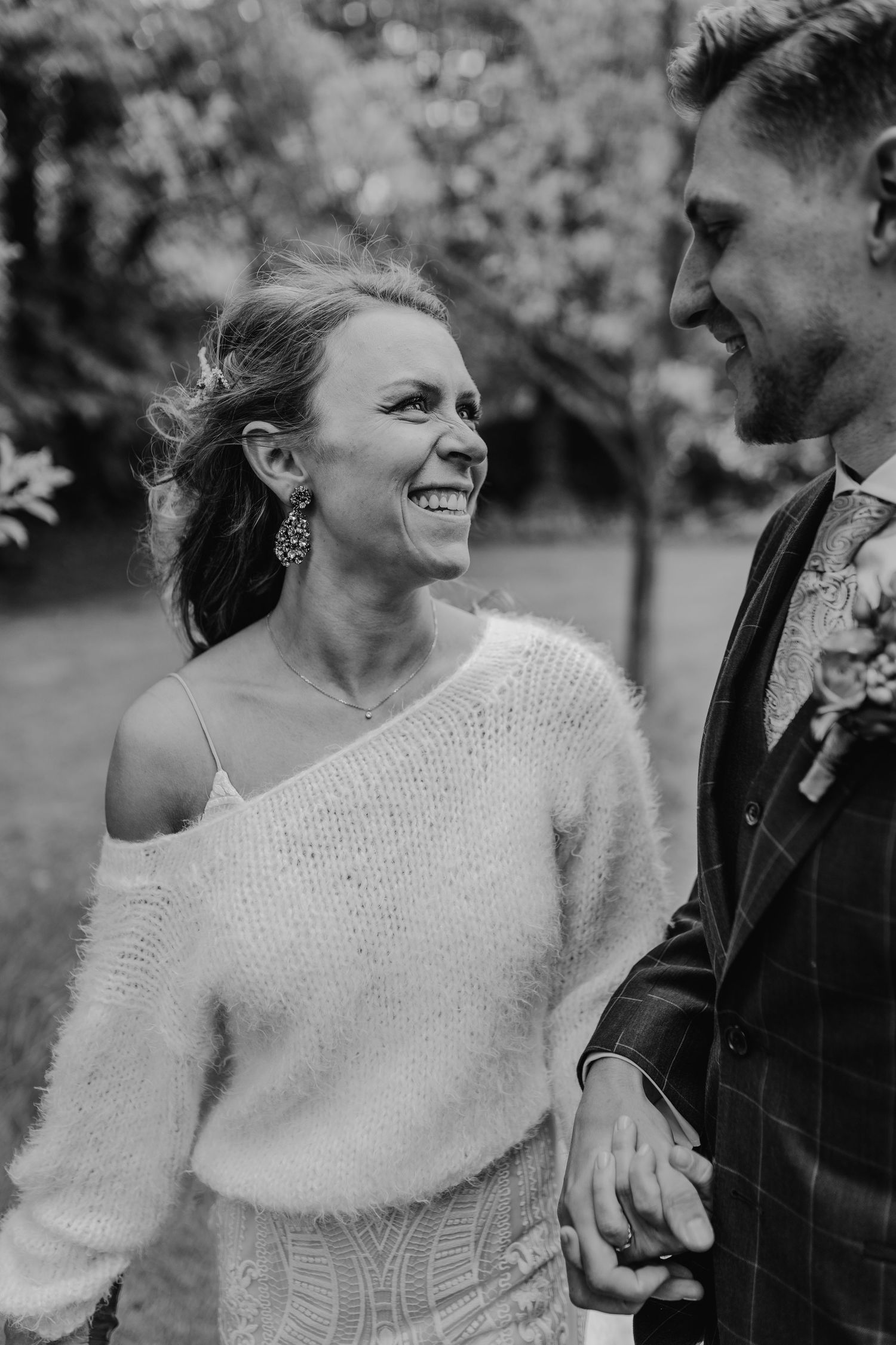 Black and white candid dancing moment with couple in wedding attire surrounded by autumn scenery.