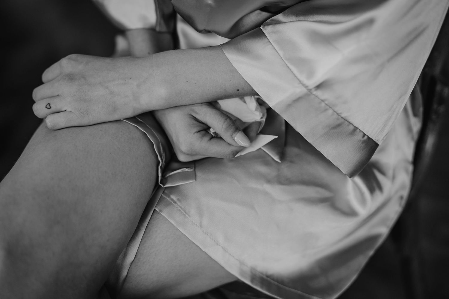 Hands delicately placing gold jewelry pieces onto a soft white surface.