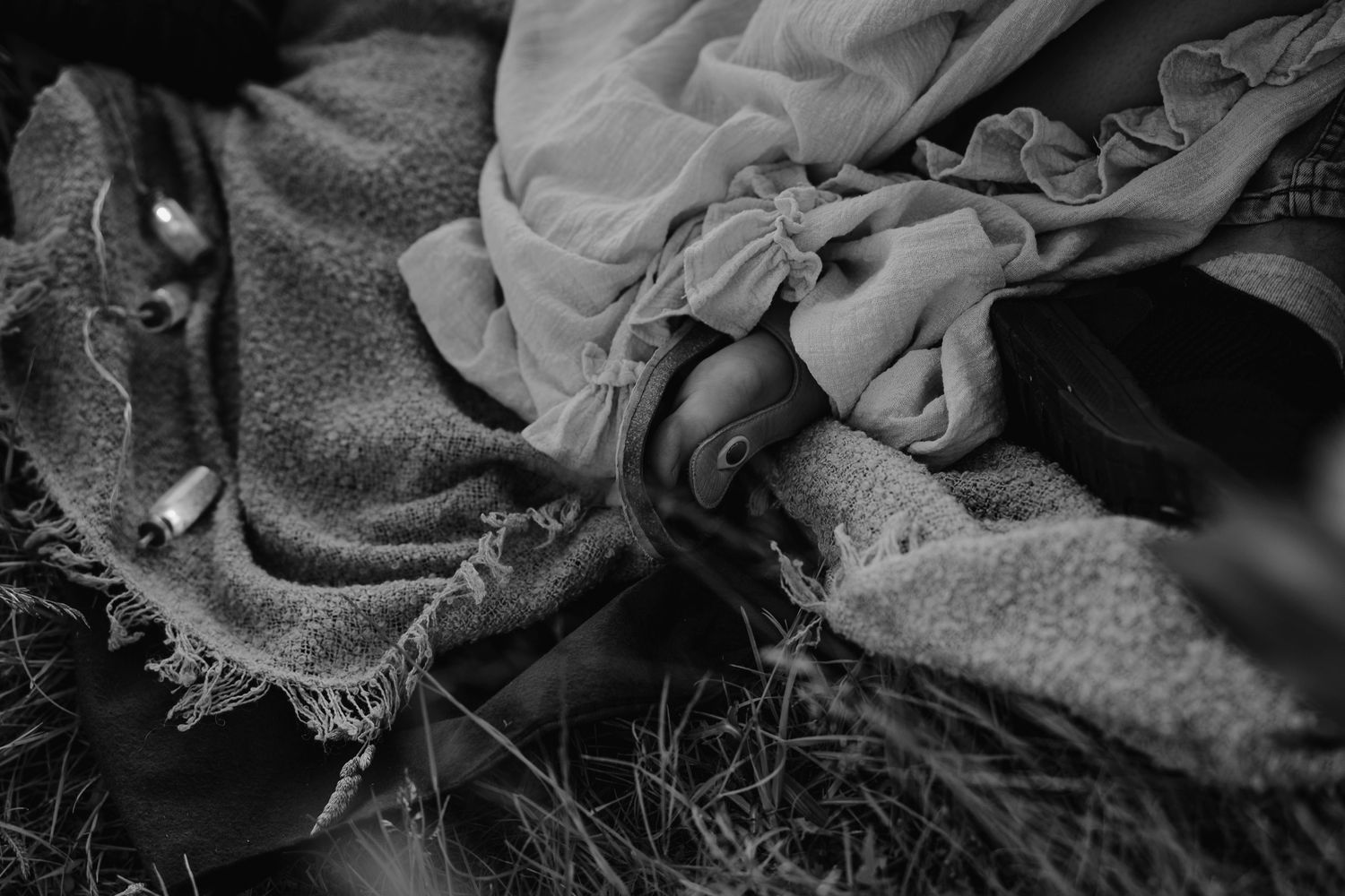 Close-up black and white photograph showing tattered and torn fabric with frayed edges and intricate textures.