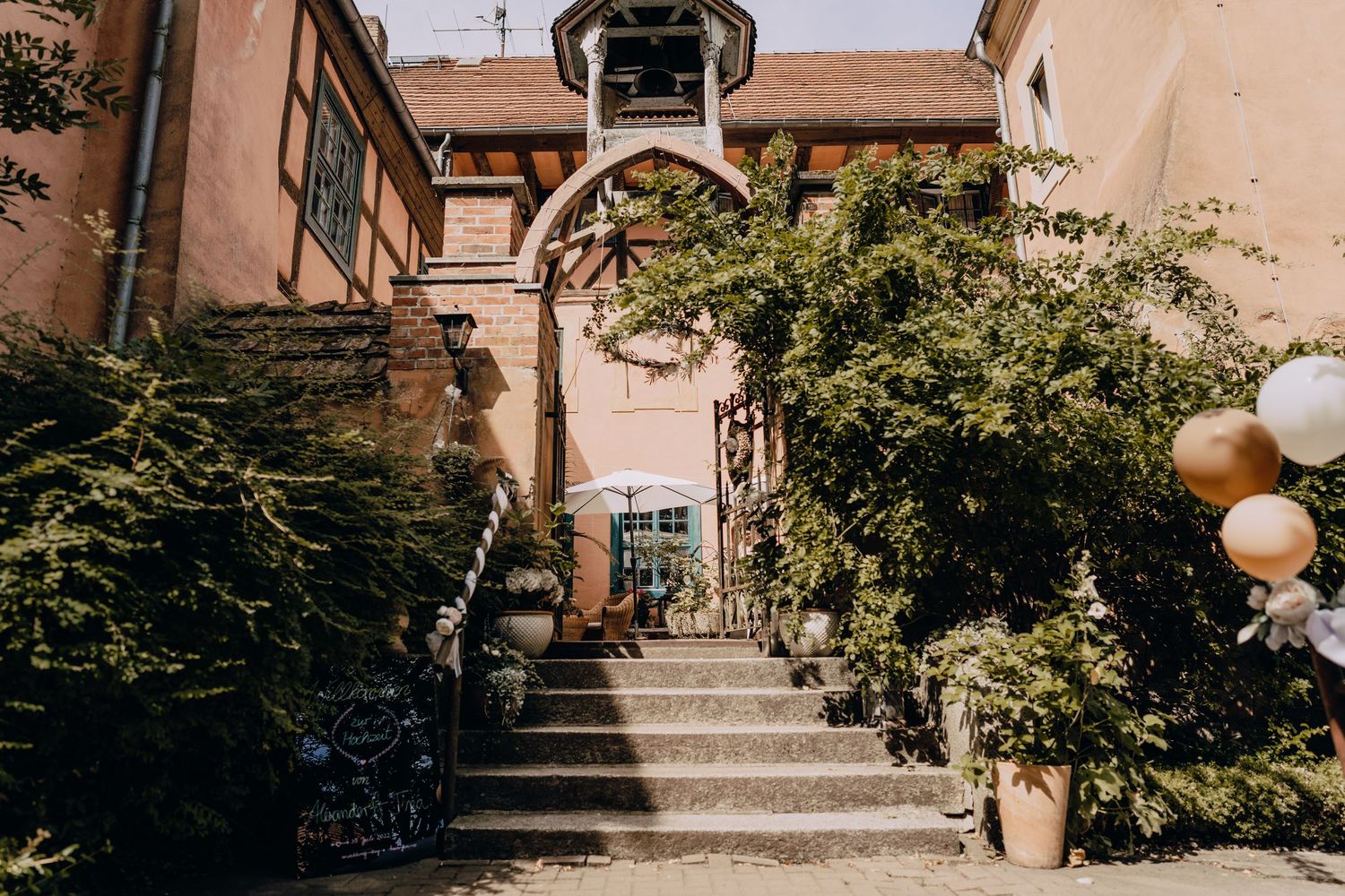 A rustic outdoor stone staircase with tan walls and hanging globe lights creates an elegant entrance.
