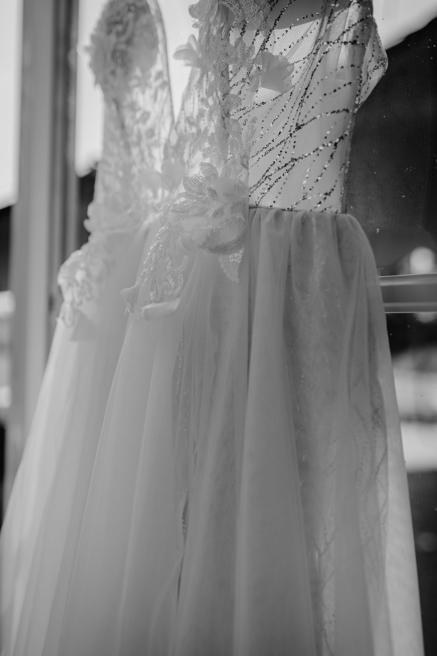 Close-up detail of a delicate white wedding dress with lace and tulle fabric in black and white.