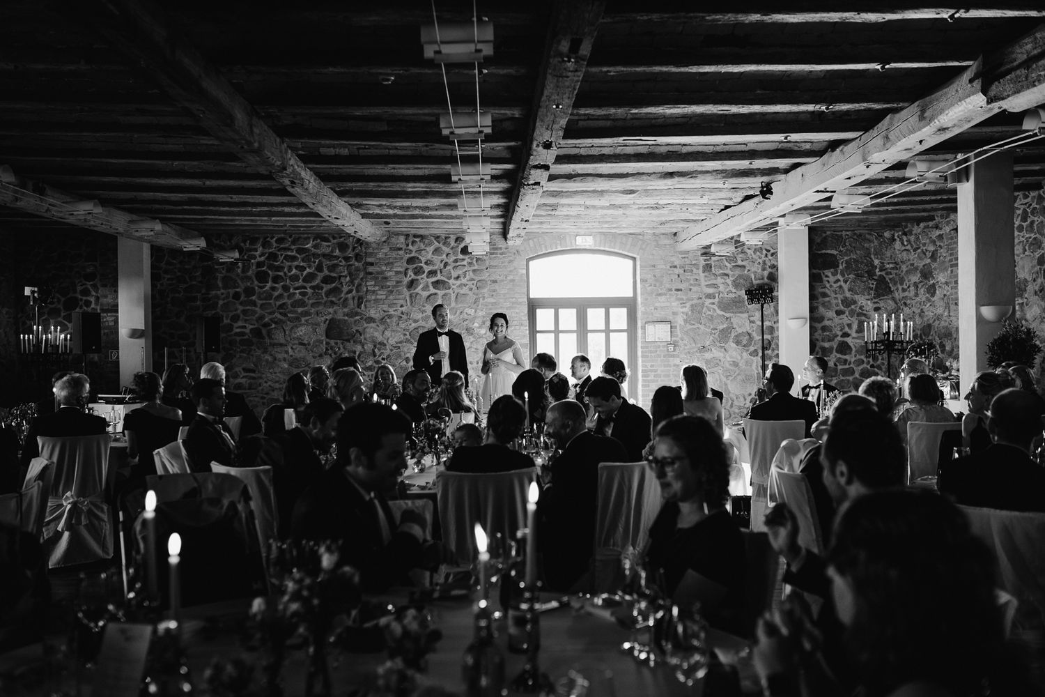 Dark nightclub interior filled with people dancing and socializing under dim lighting in multiple connected rooms.