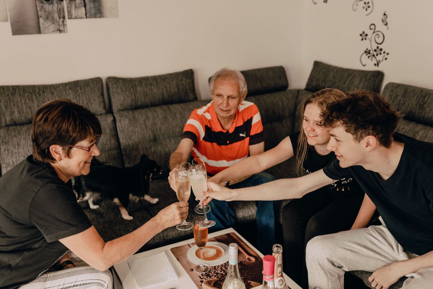 People gathering around a table playing a board game in a living room with a grey sofa.