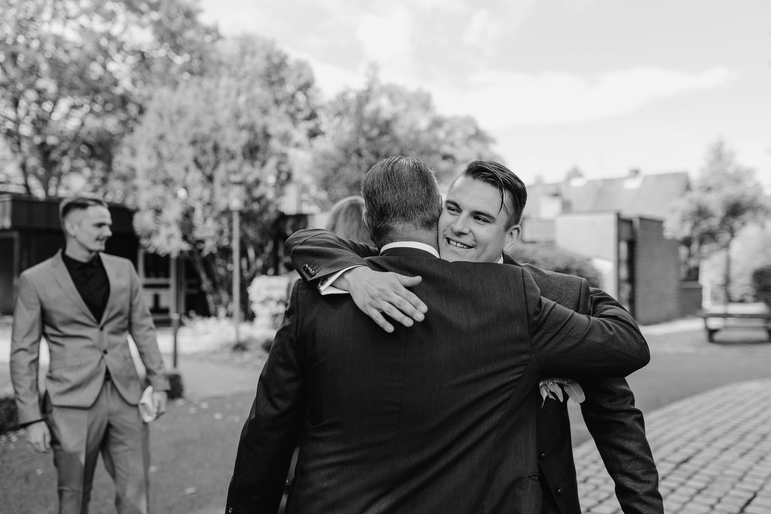 Two people walking together and embracing outside on a black and white city street.