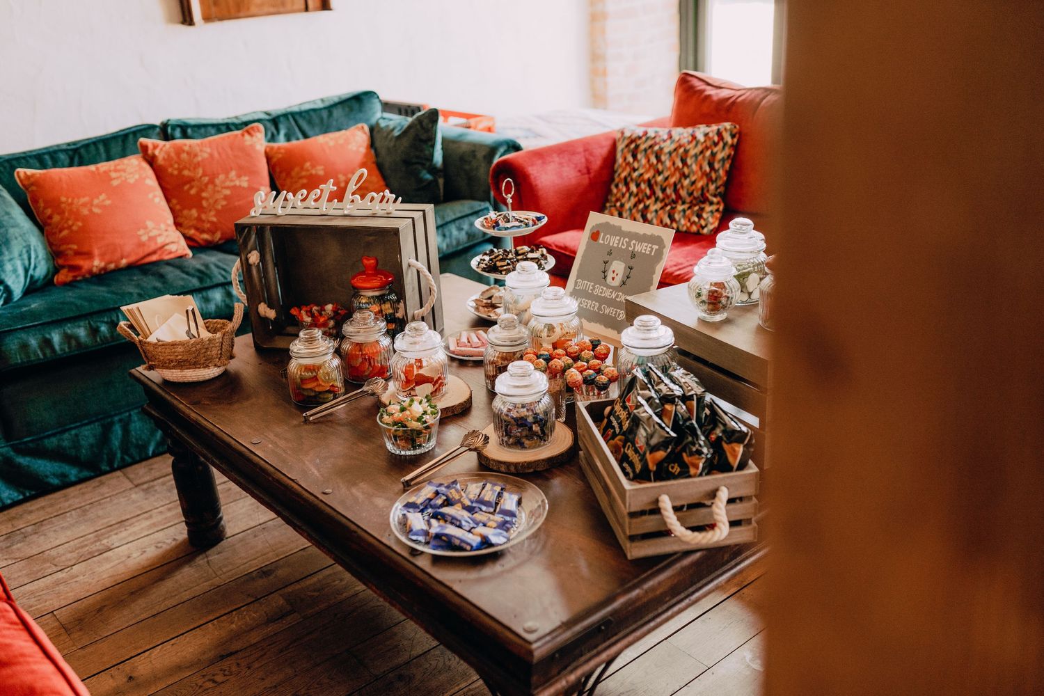 Cozy living room interior with teal and coral throw pillows on seating against wooden walls.
