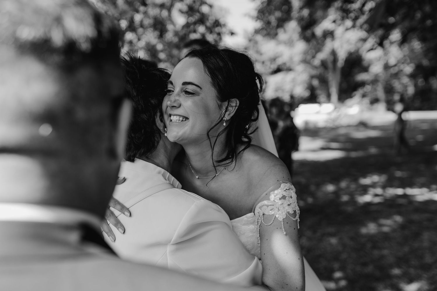 Black and white candid portrait of bride laughing during outdoor wedding celebration.