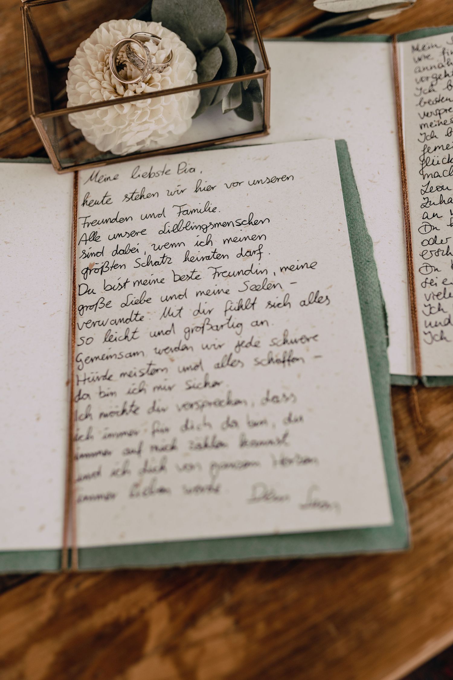Handwritten wedding vows or letter in journal with rings and floral decoration.