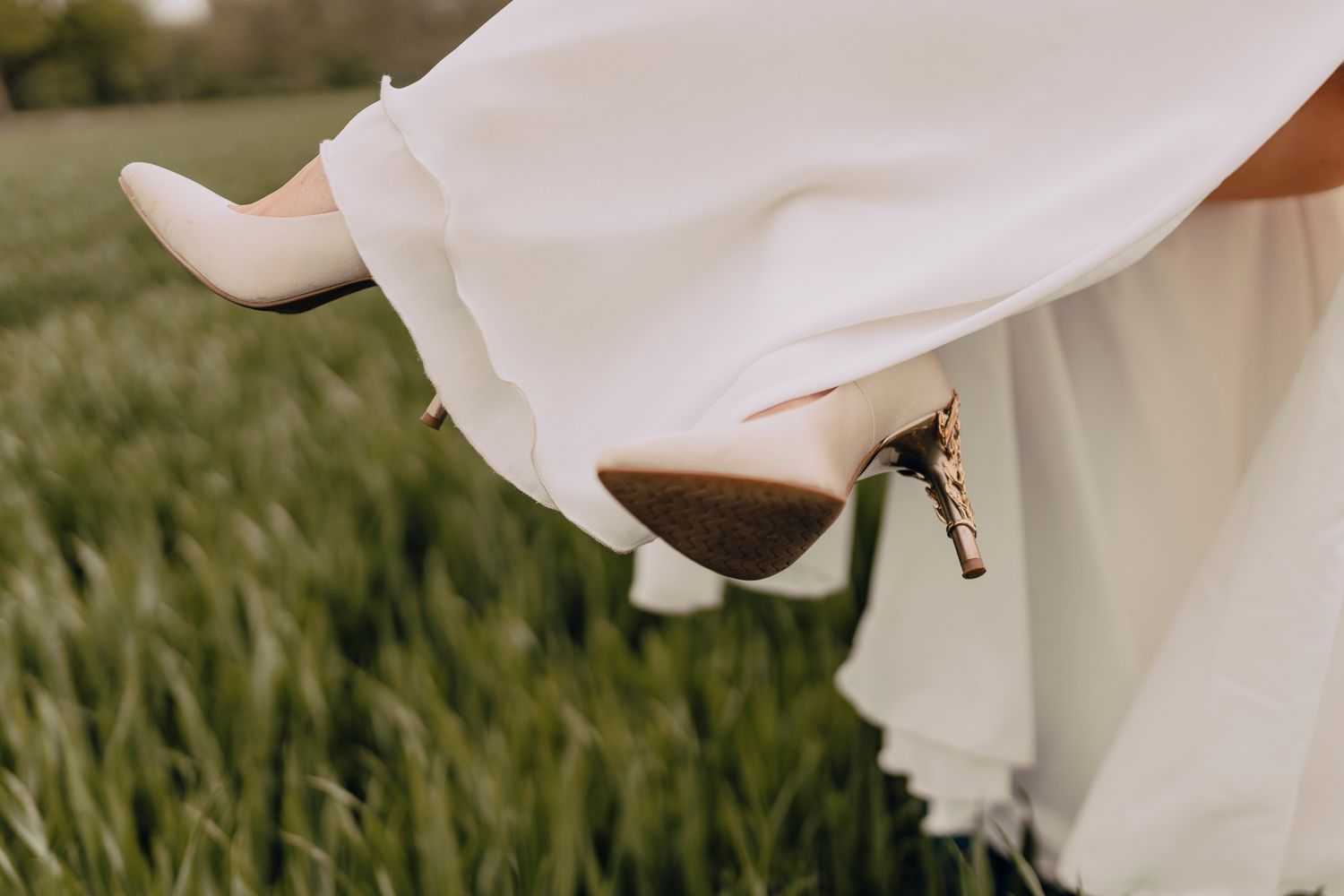 A delicate white wedding veil flutters gracefully in the breeze against a green grassy background.