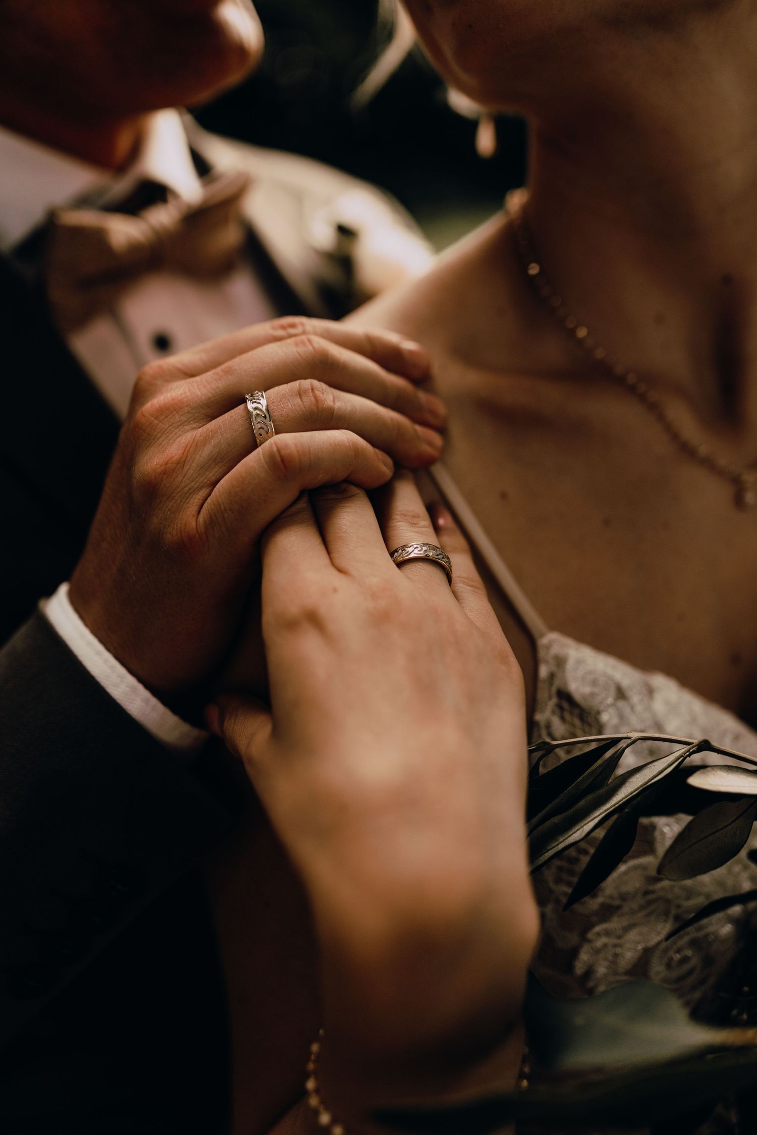 Close-up shot of hands with wedding rings in intimate moment.