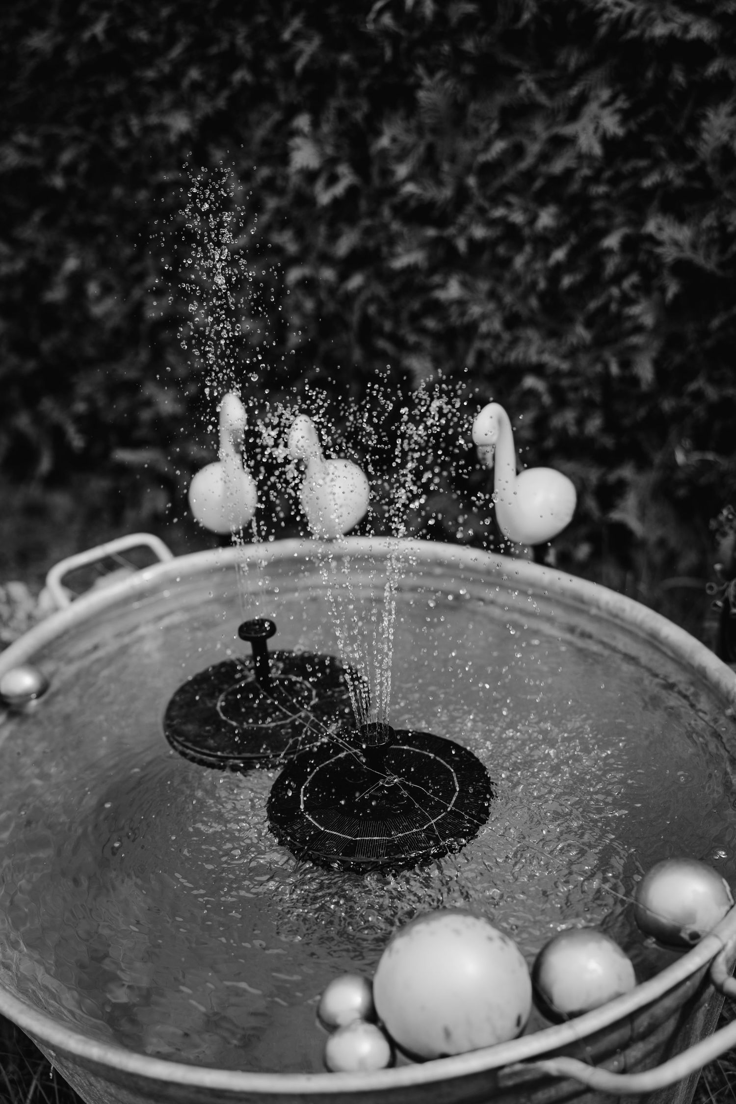Black and white photo of water bubbles and balls floating in a decorative fountain display.