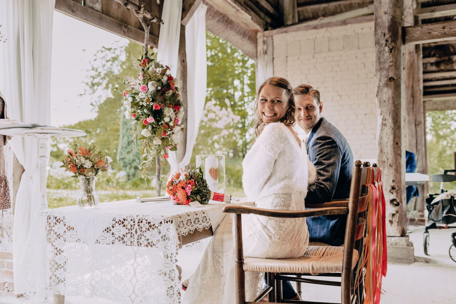 Wedding celebration in a rustic barn venue decorated with string lights and floral arrangements.