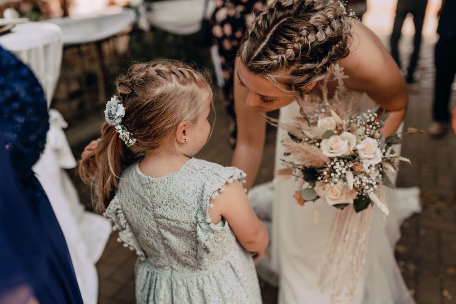 Bride in white dress holding bouquet at outdoor rustic garden wedding celebration.
