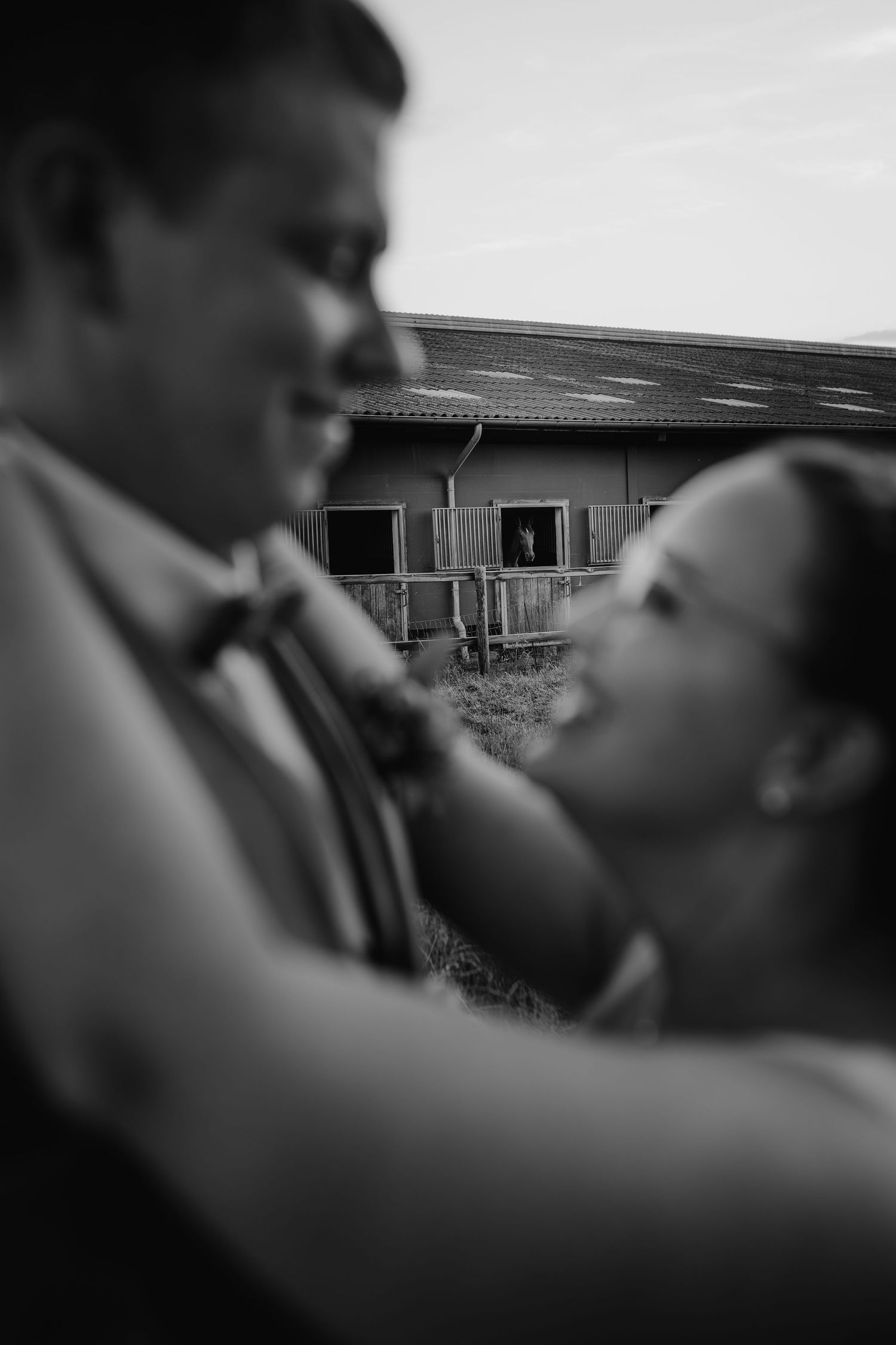 Black and white romantic photo showing a couple laughing together in an intimate moment outdoors.