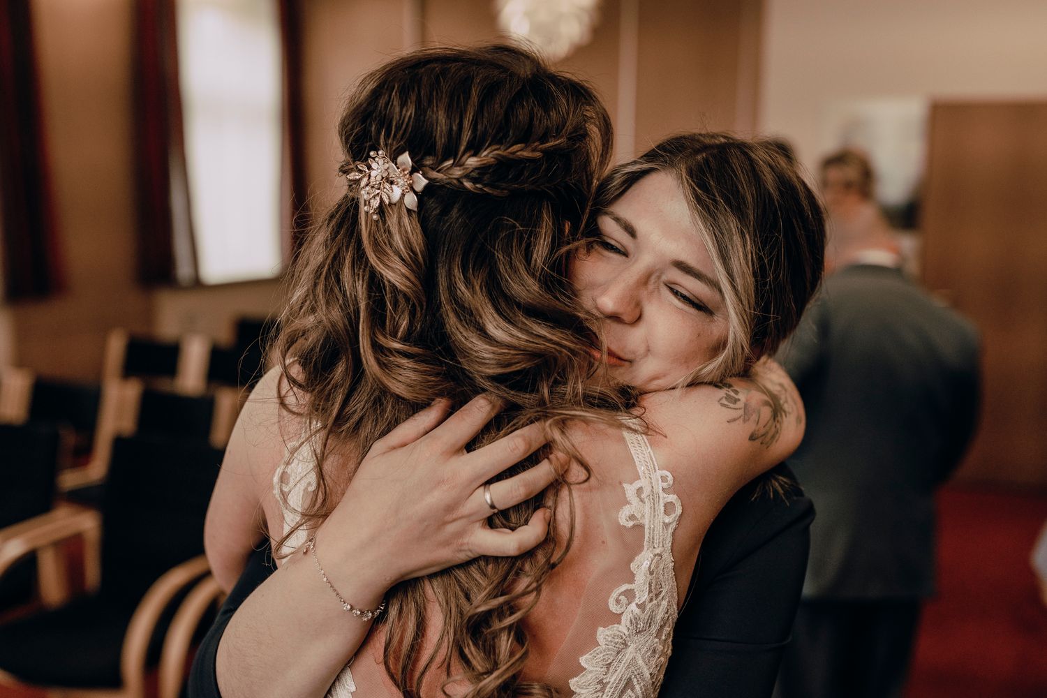 Two people in wedding attire share an emotional embrace during a ceremony in a church setting.