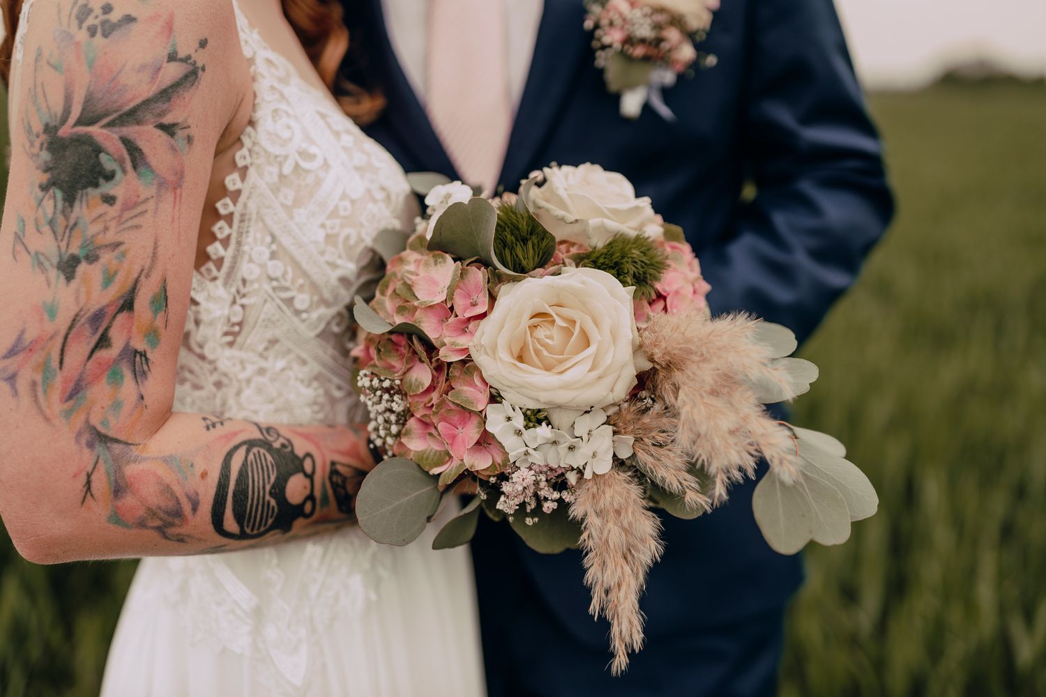 Two people sharing a kiss during their wedding ceremony with blush pink and white floral bouquets.