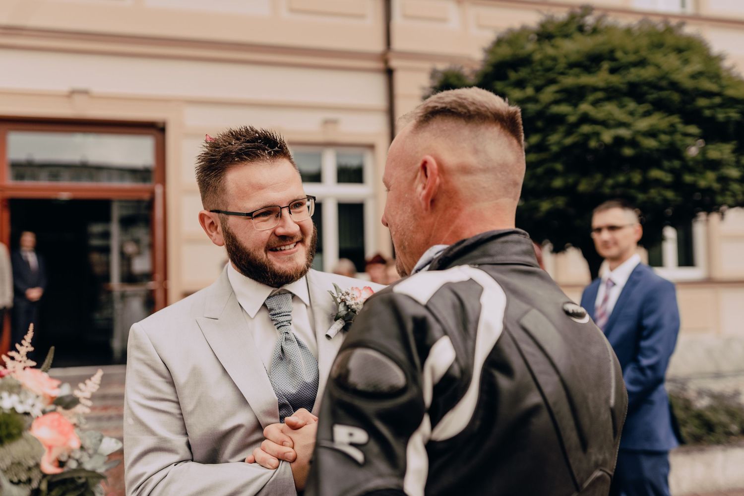 Two people sharing a joyous moment at an outdoor wedding ceremony with a building in the background.