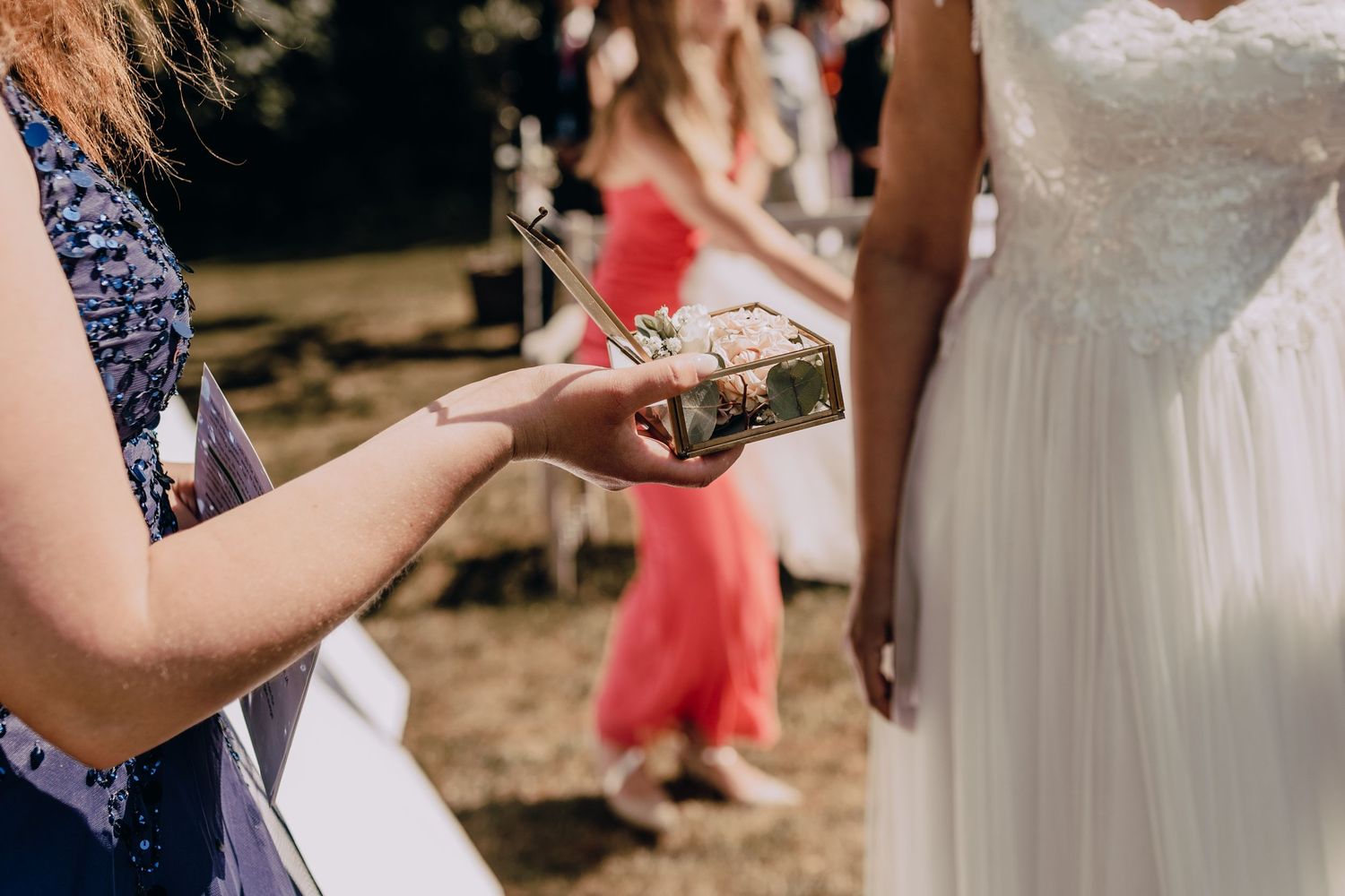 Close-up of wedding rings being presented during outdoor ceremony.