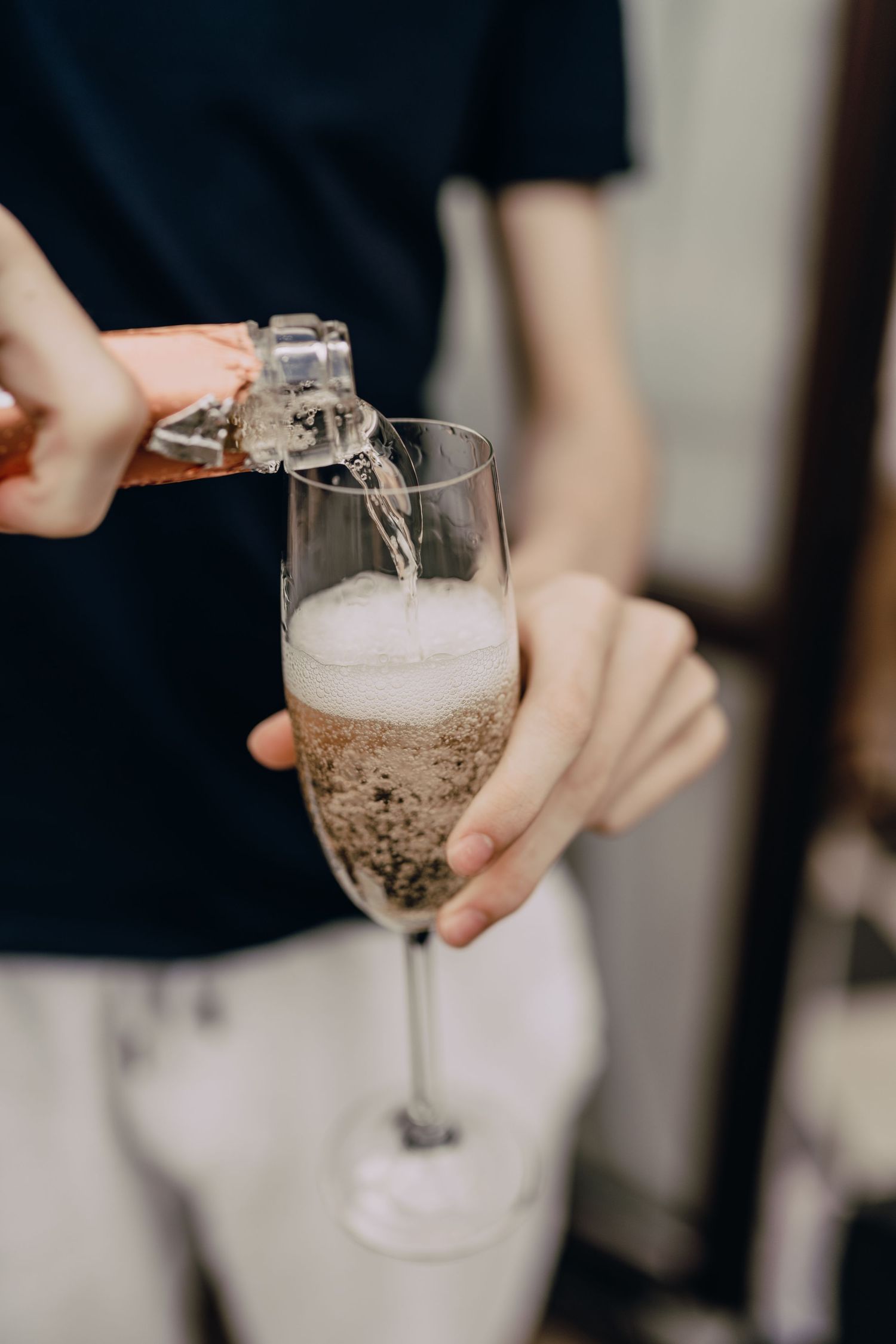 Champagne being poured into a tall flute glass creating bubbles and foam.