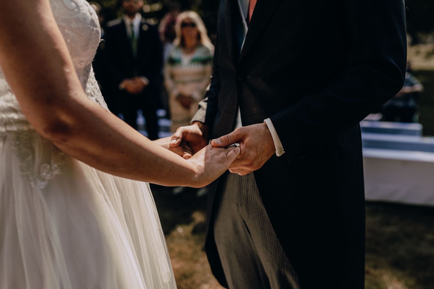 Close-up of hands holding during an outdoor wedding ceremony.