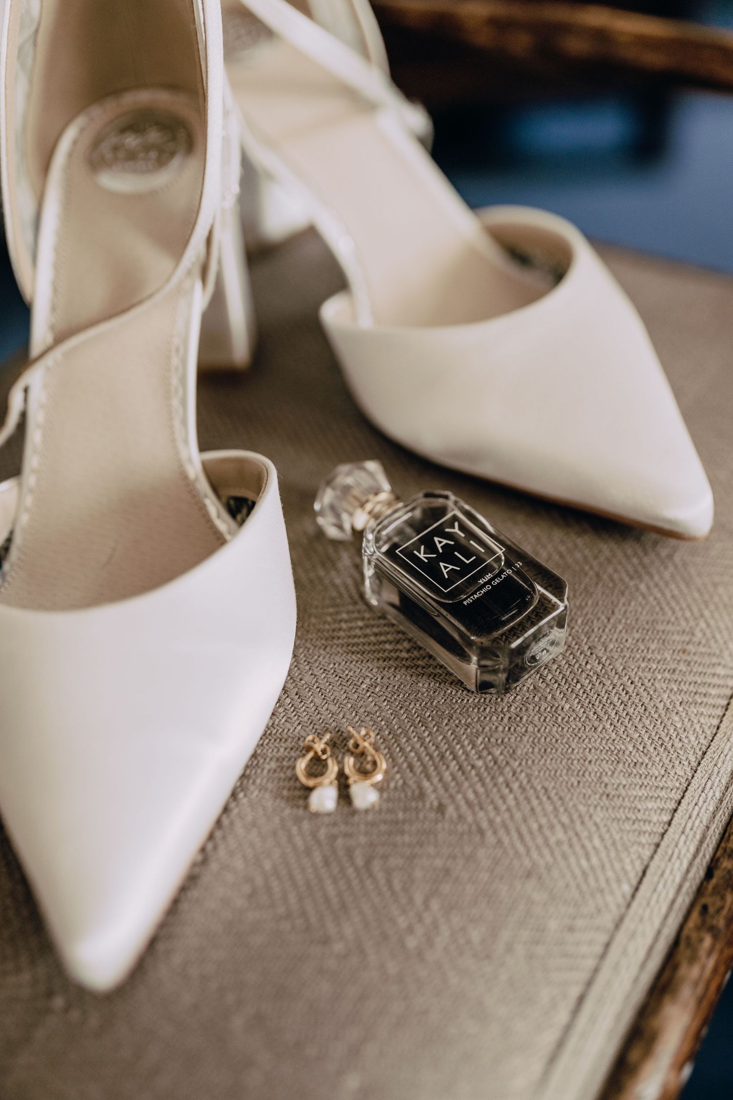 White bridal shoes and accessories arranged artistically on a textured neutral surface.