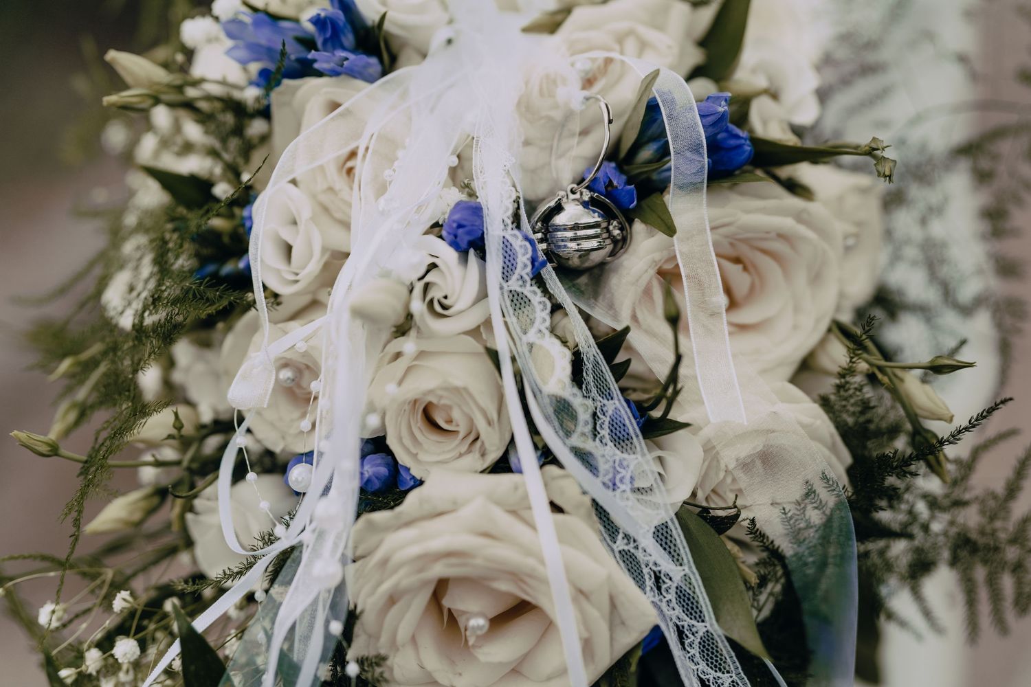 A stunning bridal bouquet features ivory roses and royal blue delphinium flowers with silver accents.