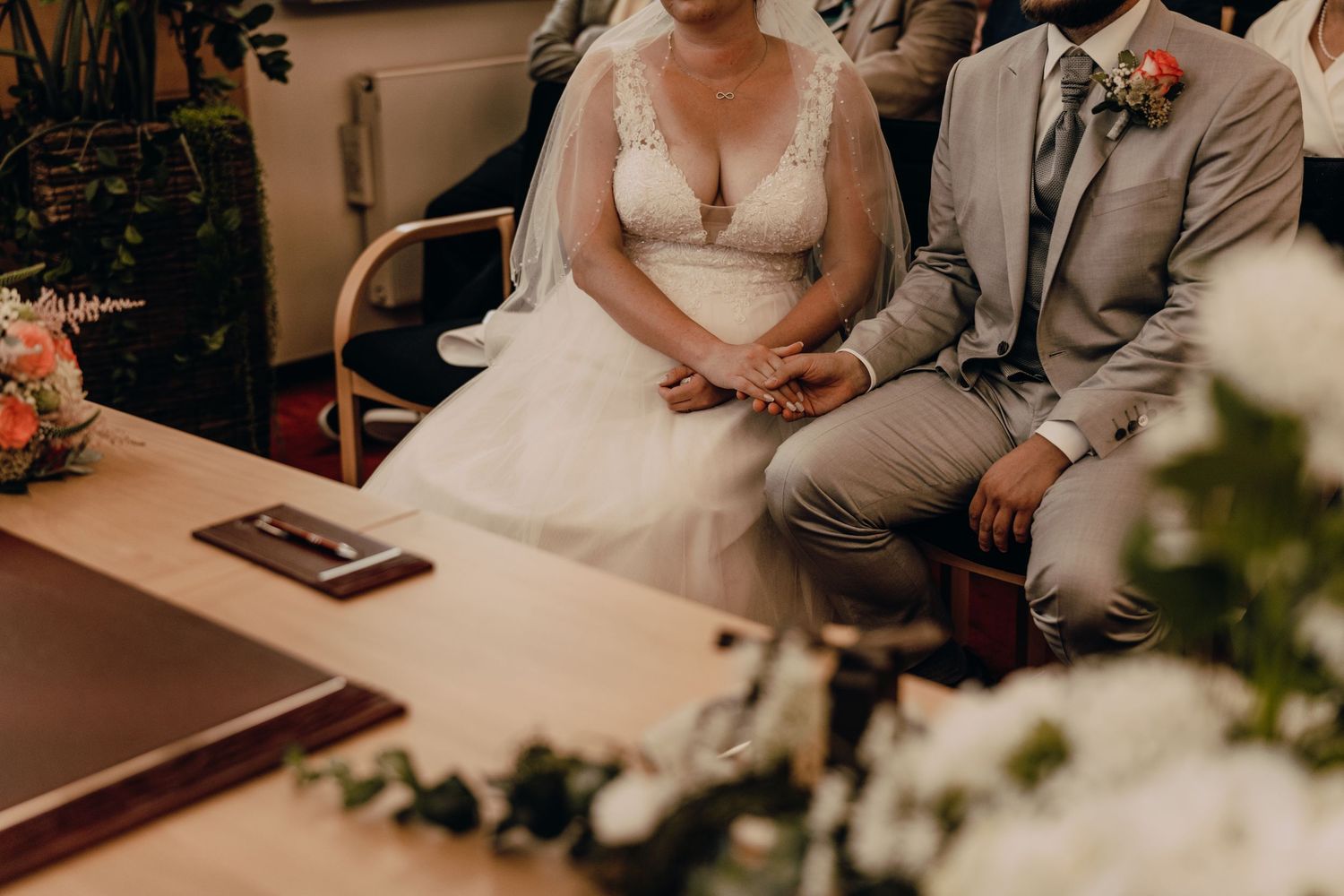 Couple seated during wedding ceremony with floral decorations.