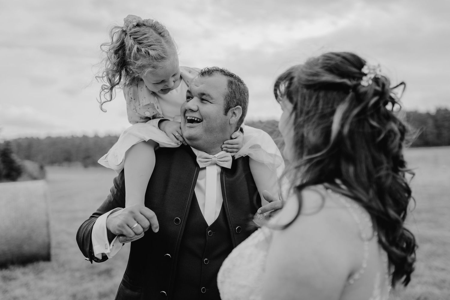 A joyful family moment captured in black and white outdoors.