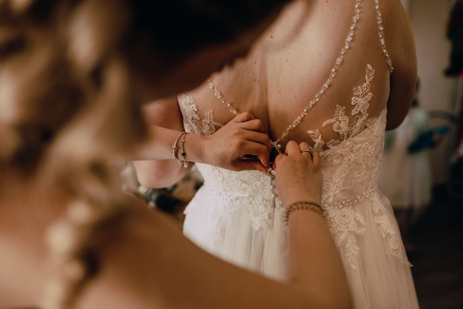 A delicate ivory lace wedding dress detail shown in warm lighting.