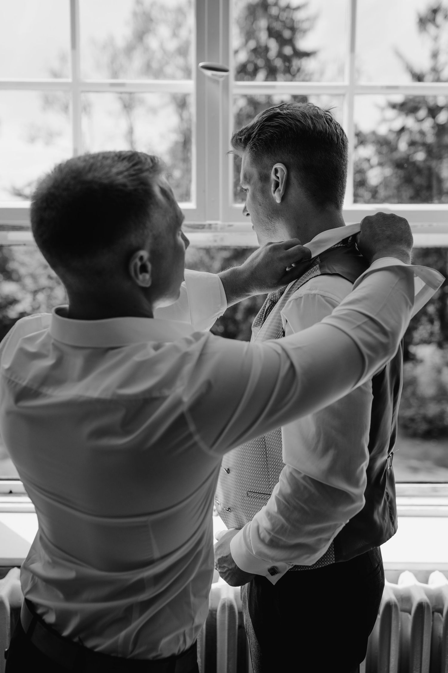 Three black and white photos showing two people sitting together by a window, sharing a tender moment.