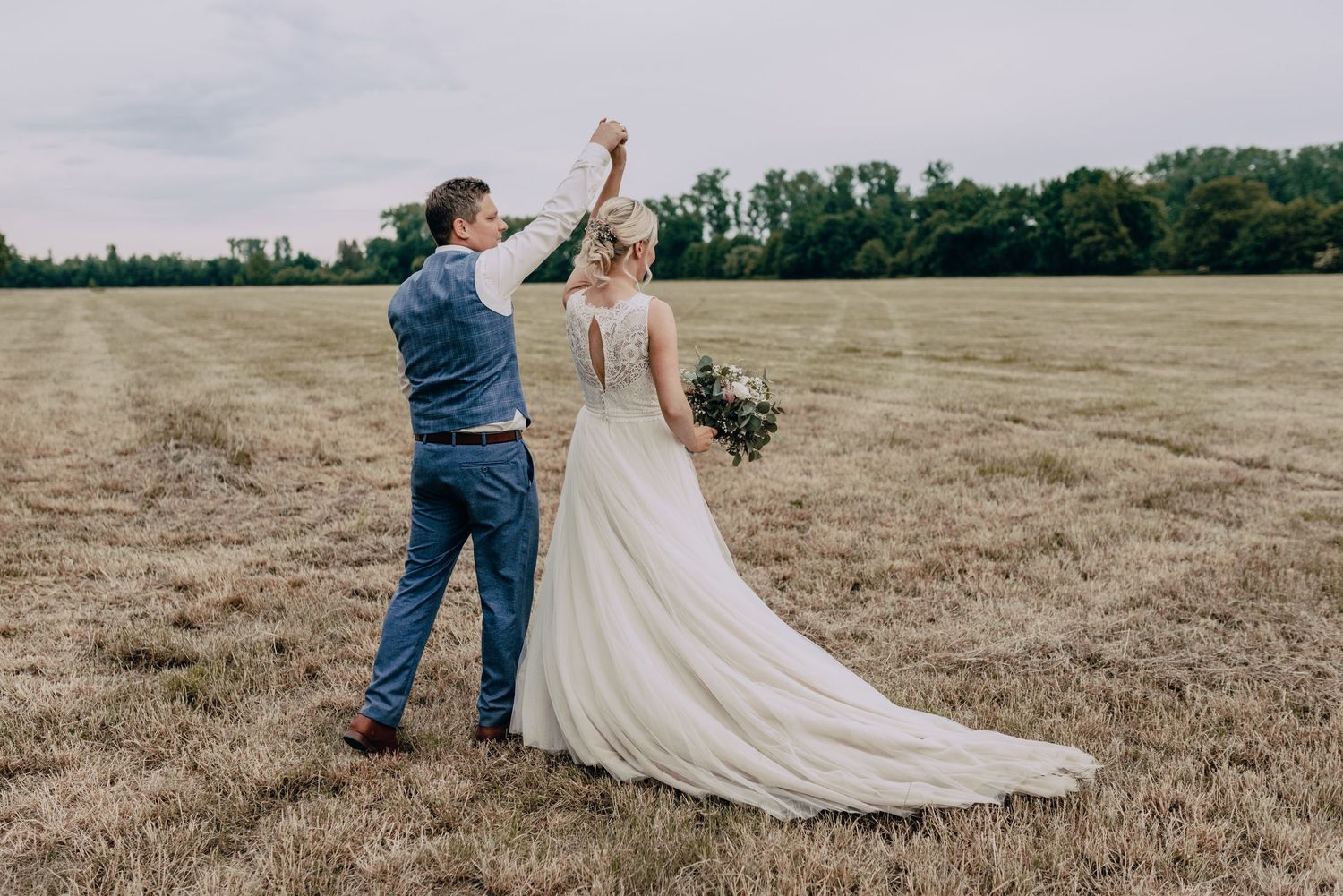 A couple dances and twirls together in an open field on their wedding day.