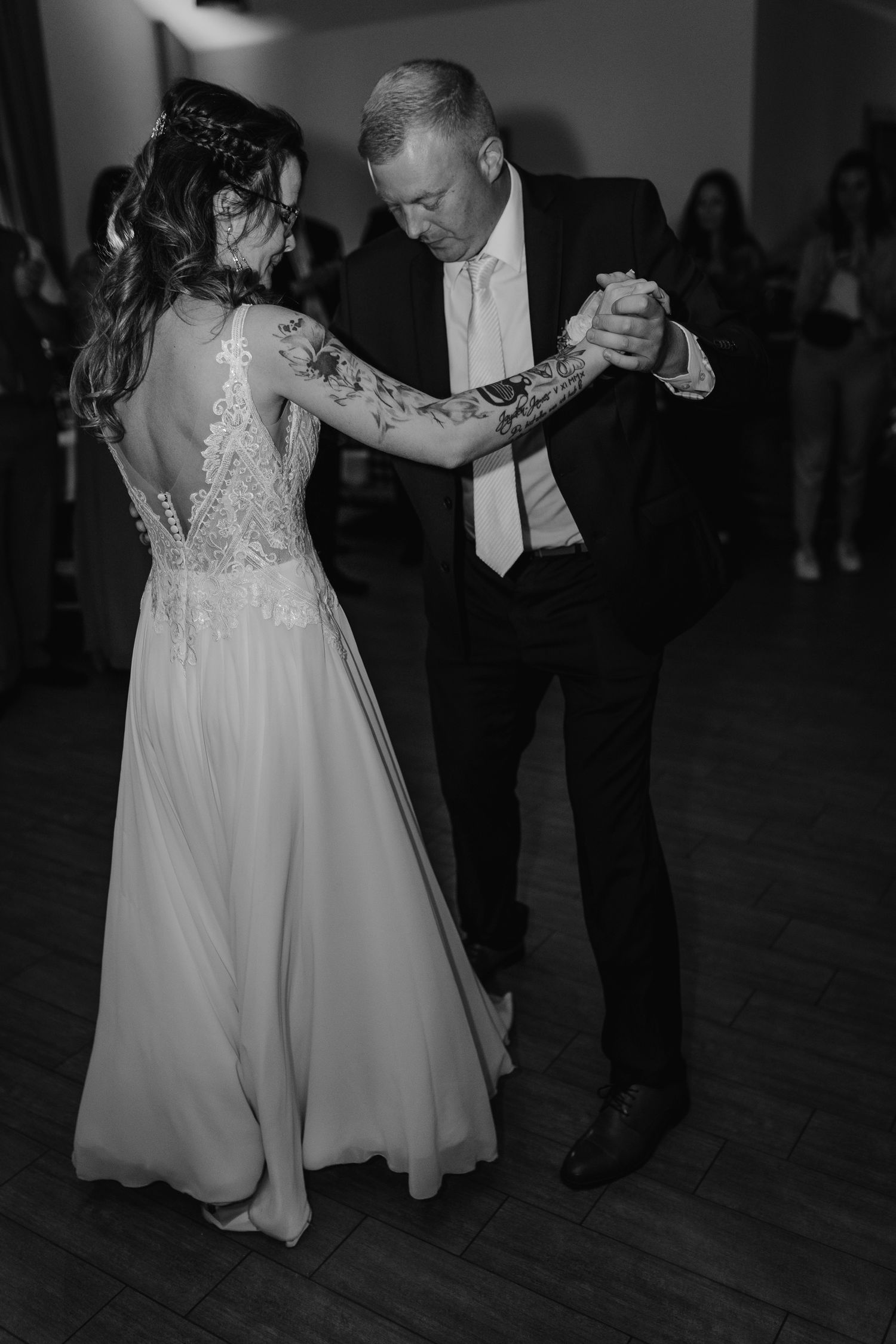 Black and white photos show a couple sharing intimate dance moments at a wedding reception on a wooden dance floor.