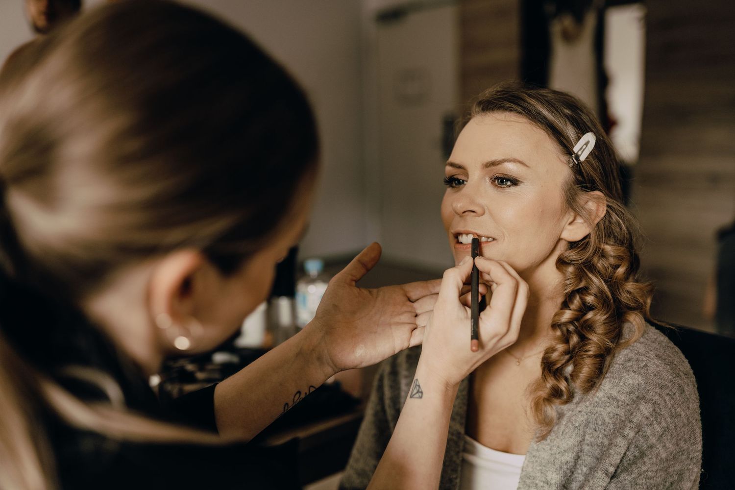Makeup artist applying lipstick to a bride during wedding day preparations.