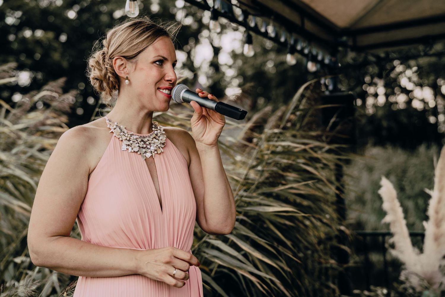Wedding celebration outdoors with pink dress and natural decor details.