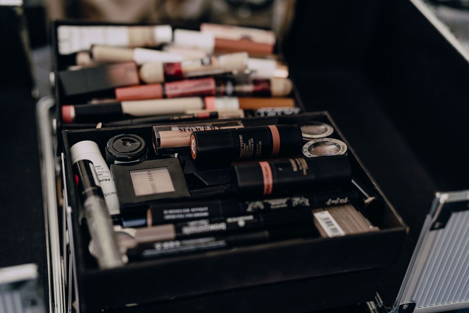 Open makeup drawer displays organized collection of neutral lipstick tubes and cosmetic products in neat rows.