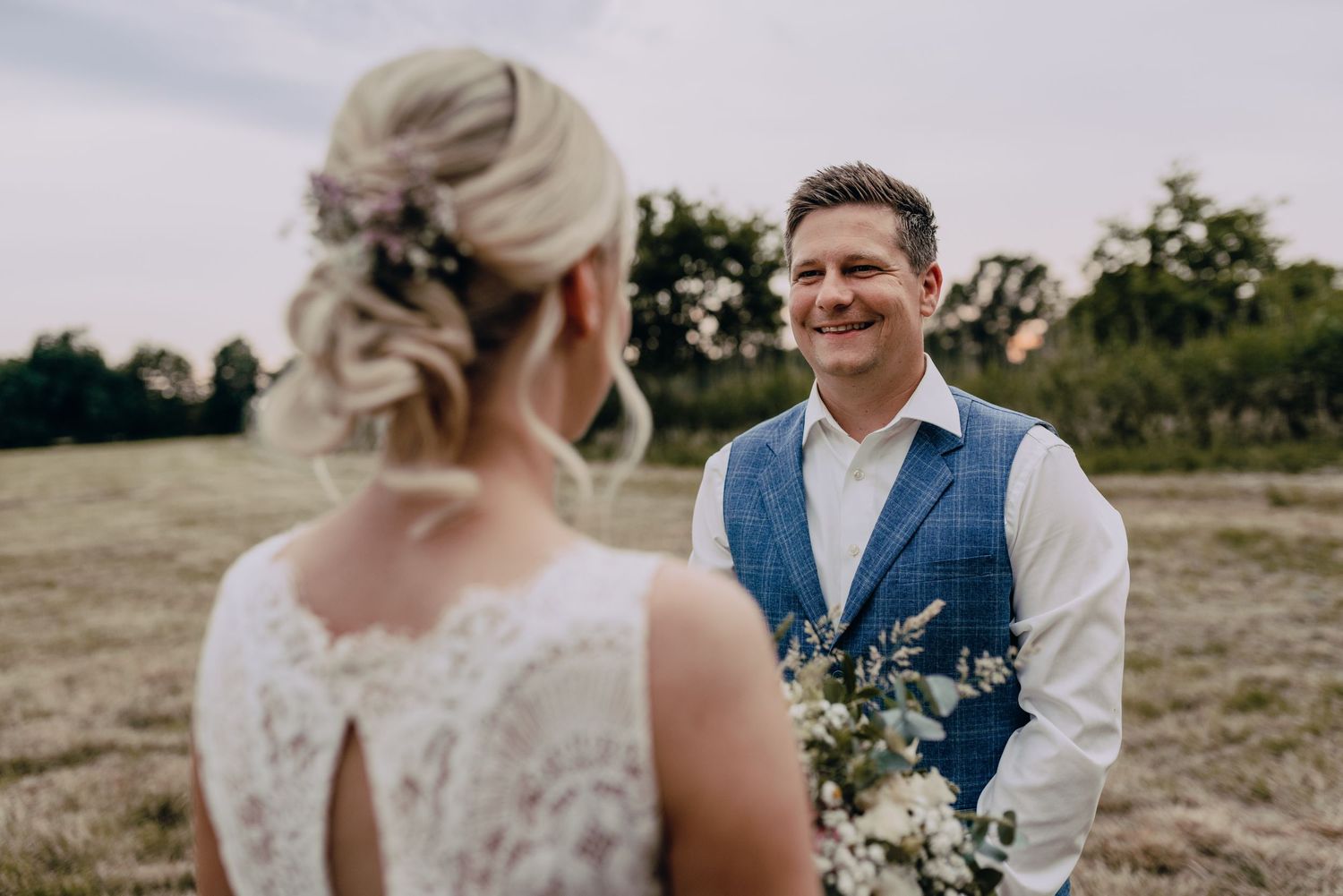 A romantic outdoor wedding portrait showing a couple sharing a special moment in a field.