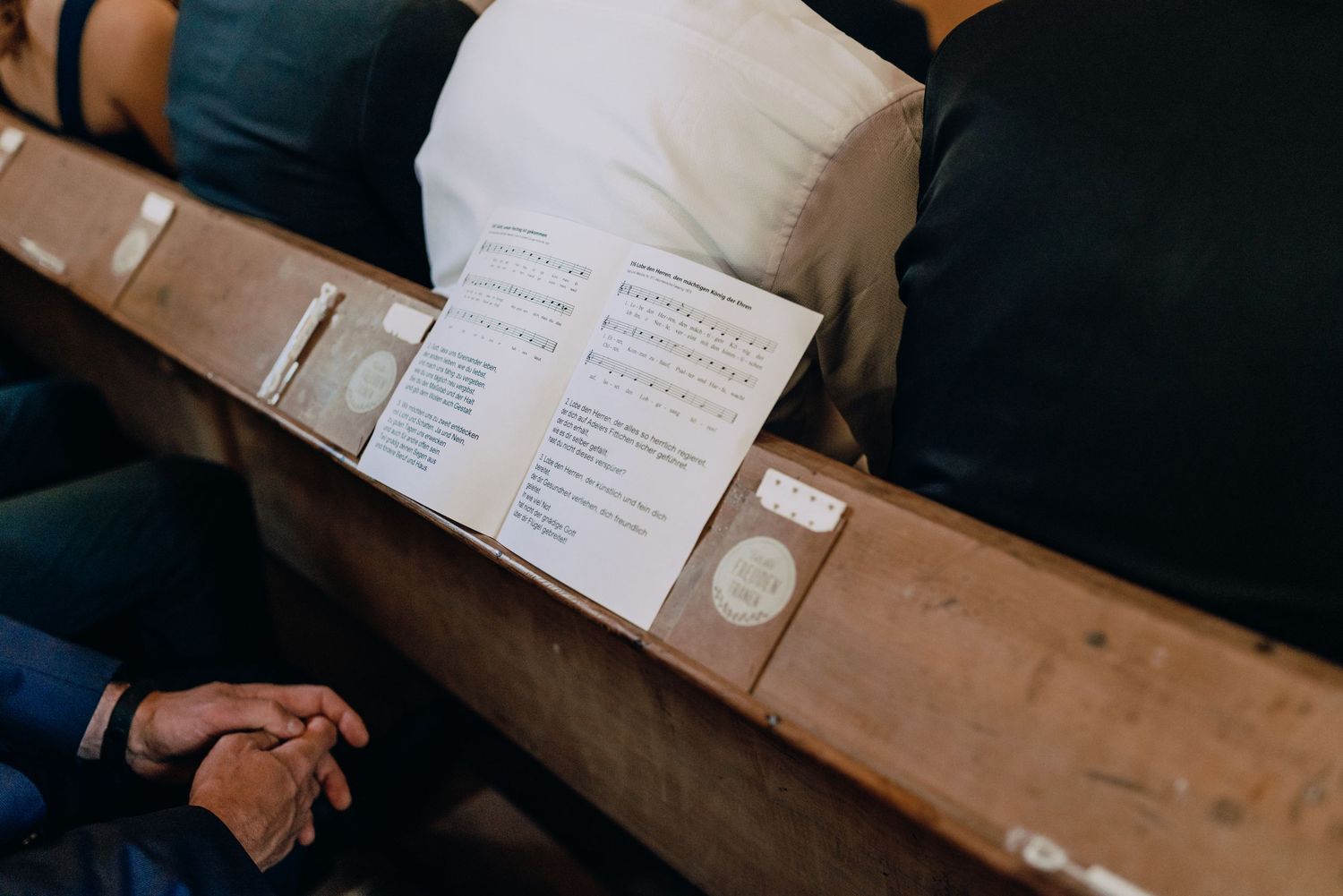 Close-up view of hands holding open wedding ceremony programs printed on beige paper.