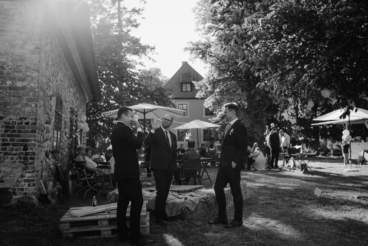 Wedding guests gathered outside a brick building on a sunny day.