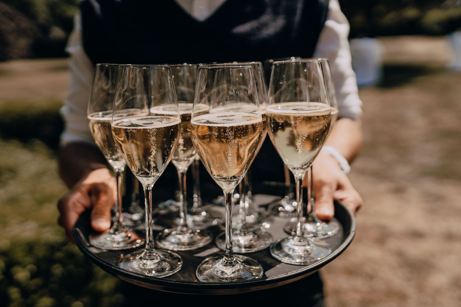 Row of champagne glasses filled with rosé being served on silver trays.
