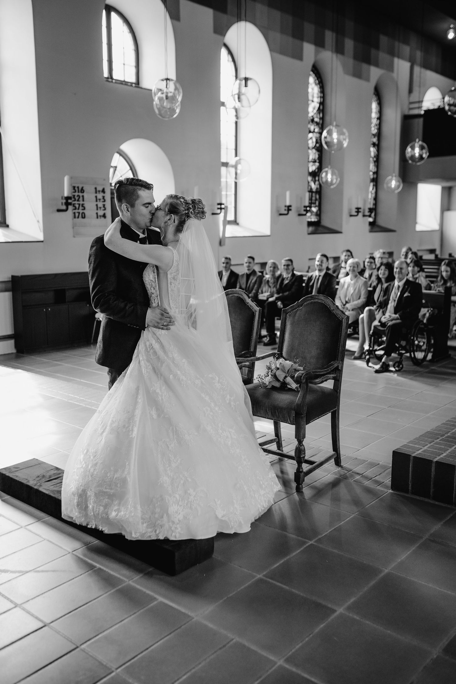Sequence of black and white photos showing a wedding dance in a grand hall with arched windows and elegant decor.
