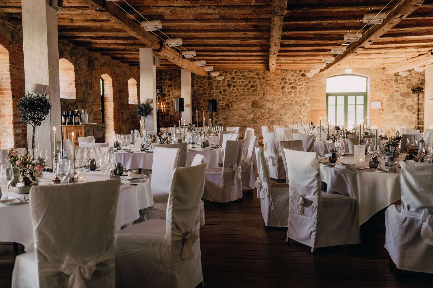 Rustic wedding reception venue with white-covered tables and exposed wooden beams.