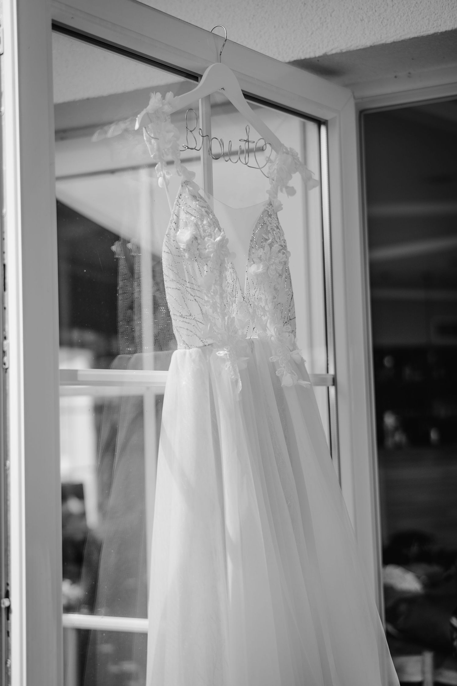 Several white wedding dresses hanging on display in a row against a light-colored wall.