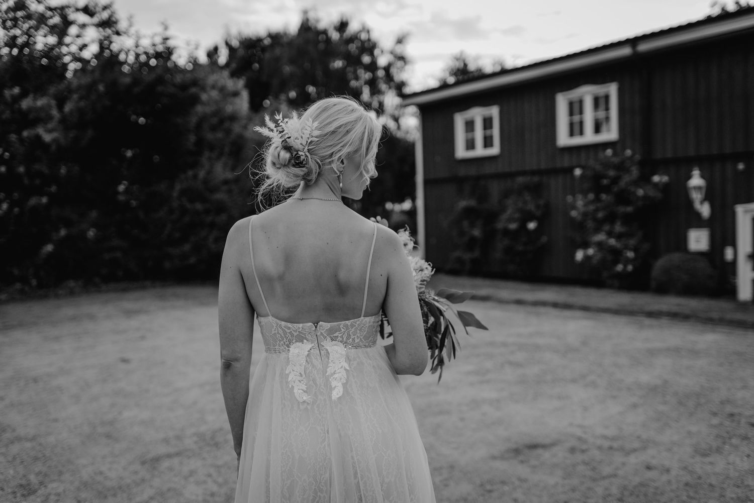 Black and white wedding ceremony scene with rows of white chairs set up outdoors.