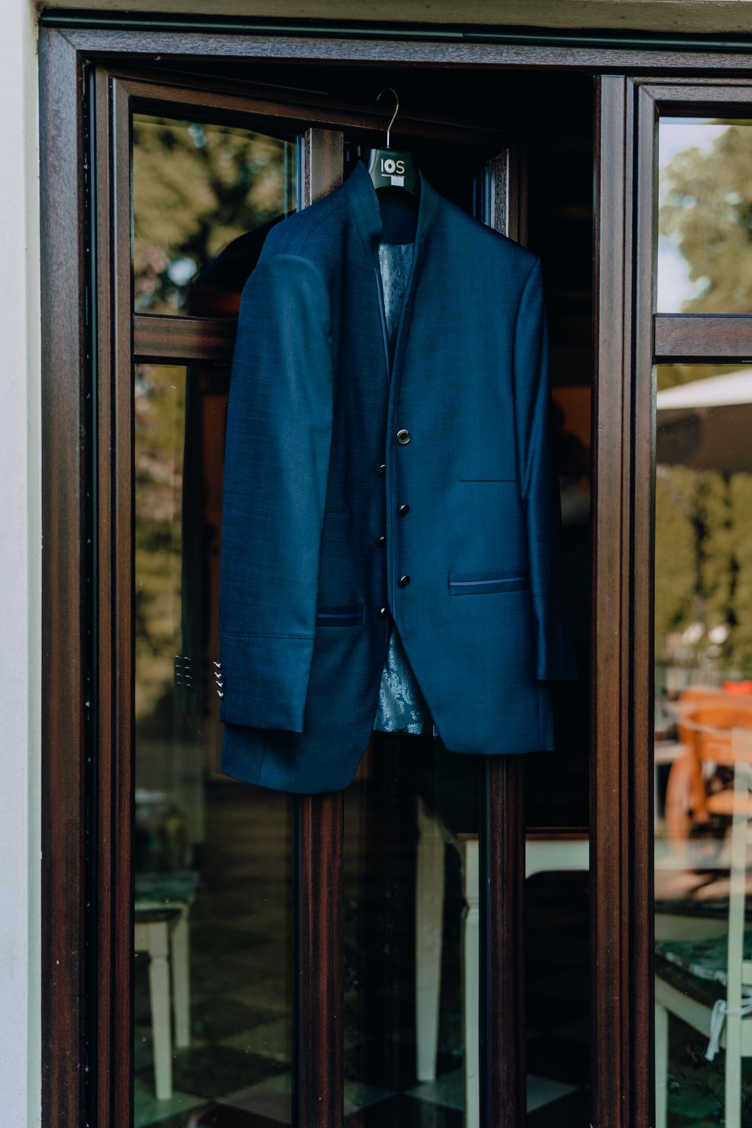 A navy blue formal suit jacket hanging in a window display.