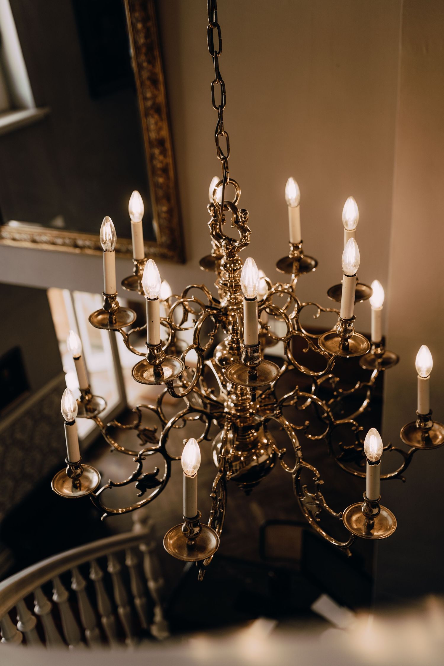 Elegant antique brass chandelier with multiple candlestick-style lights illuminating a dark room.