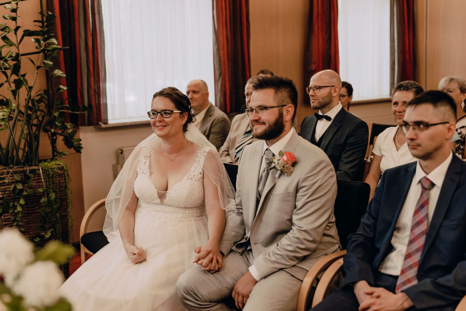 Wedding guests share joyful moments during an intimate indoor ceremony with warm lighting and rustic decor.
