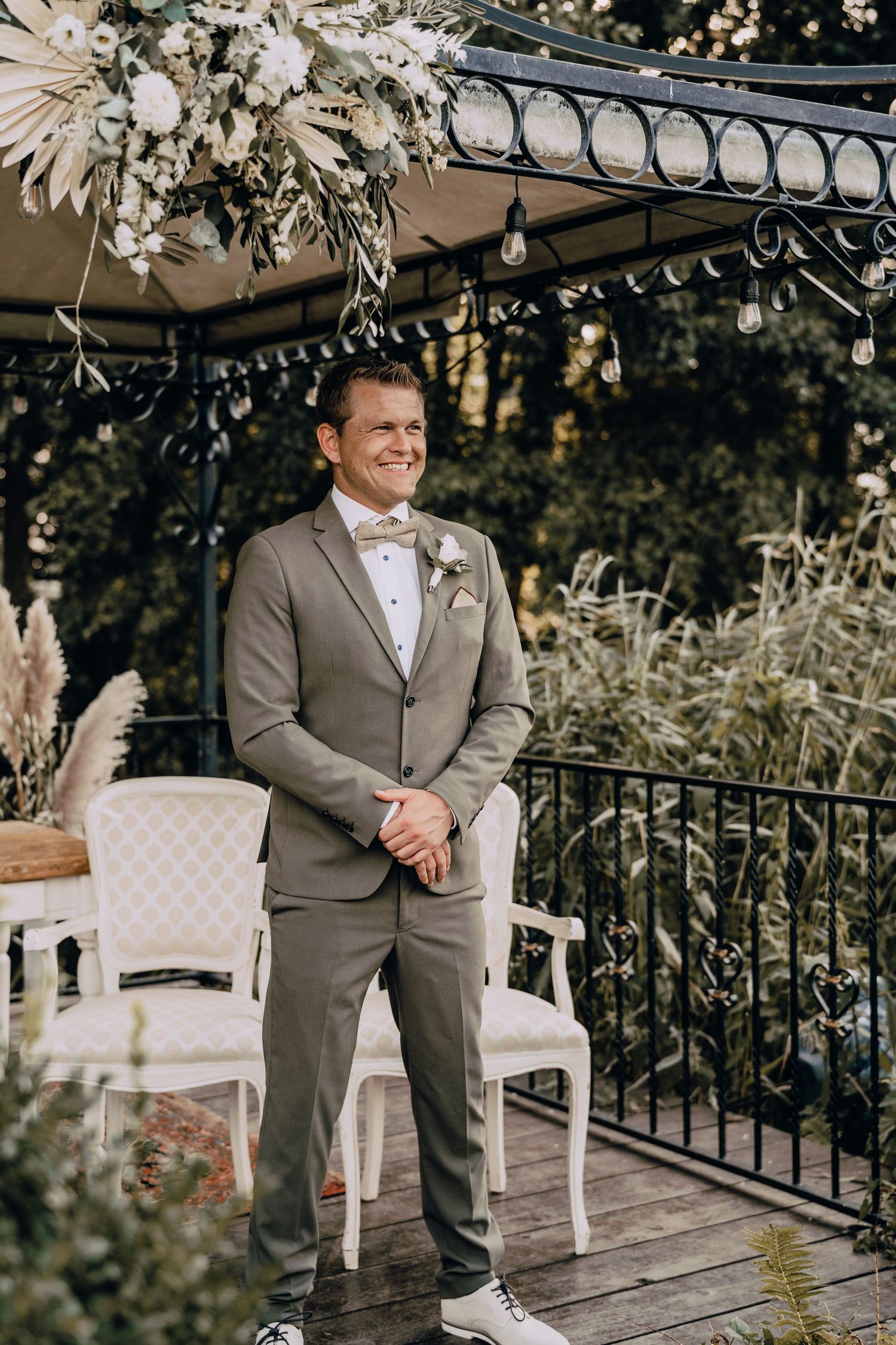 Outdoor wedding venue with white chairs and wrought iron railings decorated with floral arrangements.