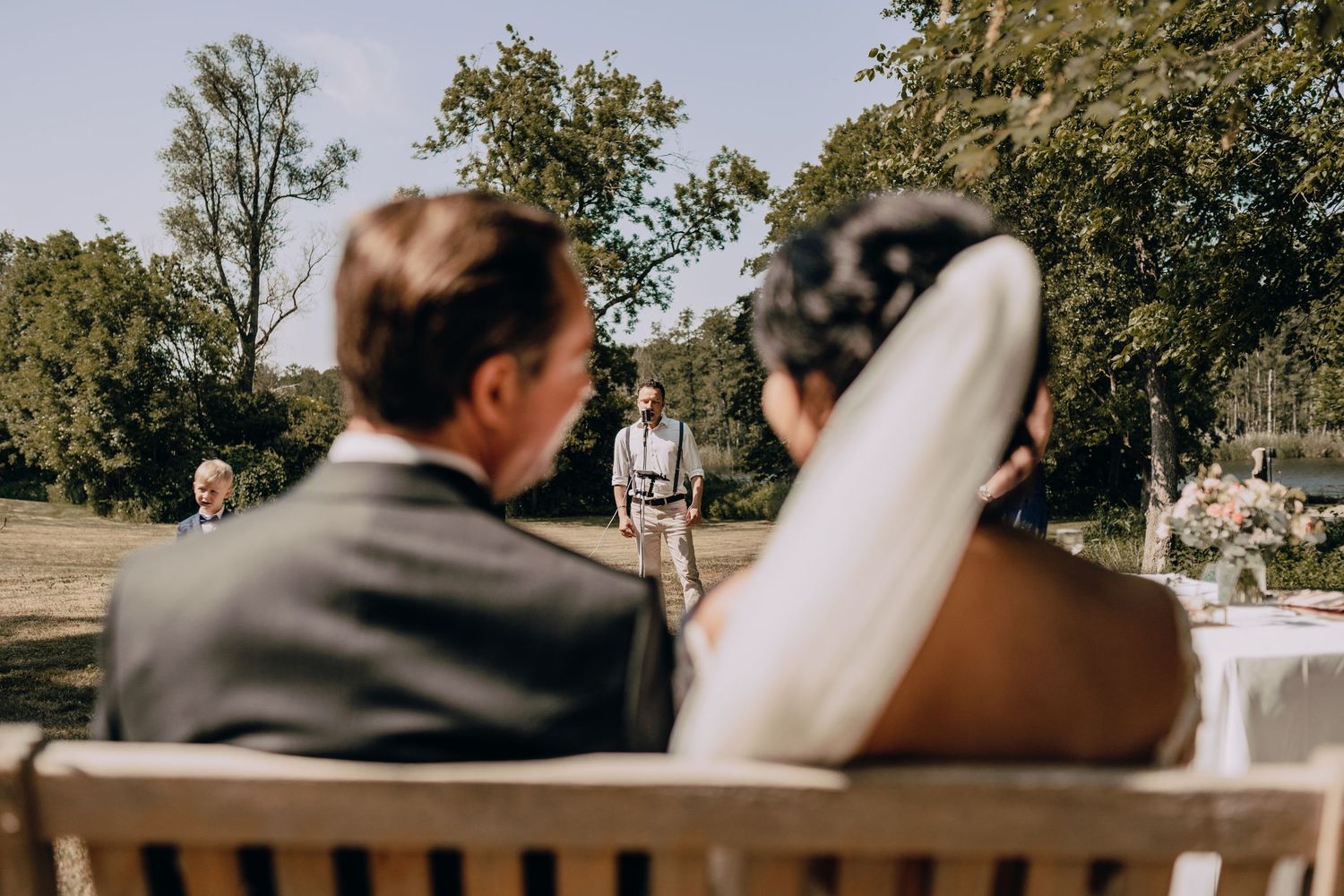 Outdoor wedding ceremony setup with white chairs arranged in rows under trees.