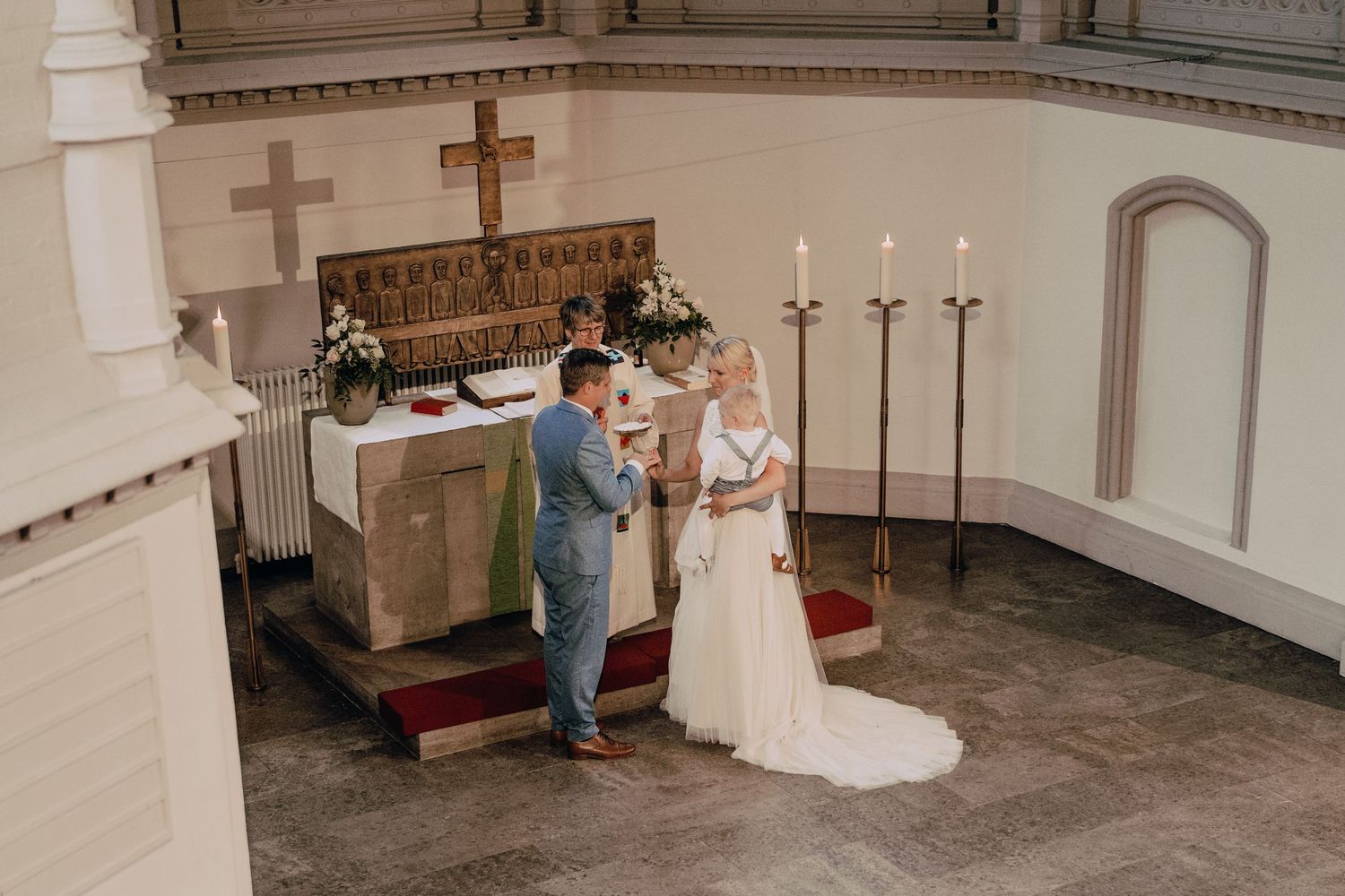 White church interior with multiple crosses mounted on wall and traditional church pews.
