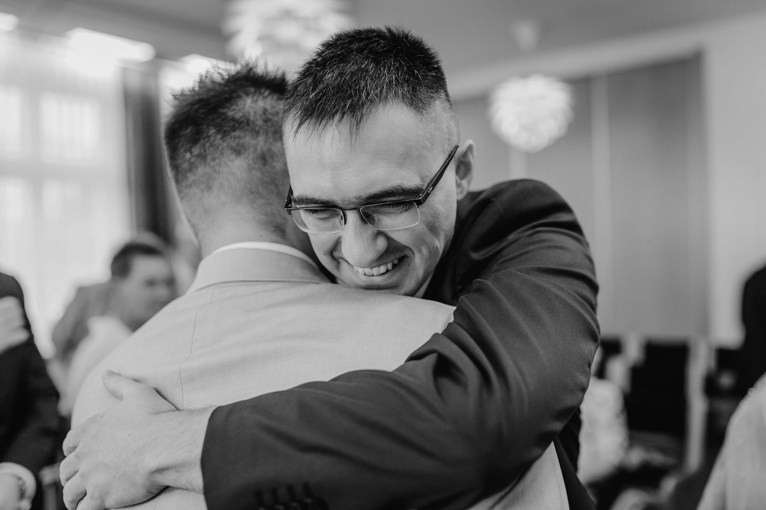 Black and white wedding photo capturing emotional embraces during a joyful celebration.